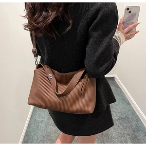 Detail of dark brown tote bag with vertical pleated leather texture and silver buckle