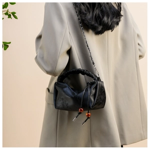 Détail du sac plissé noir avec cordon à perles ambrées et textures de motifs jacquard