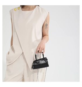 Detail of a black mini bow handbag with top handle and elegant silver chain strap