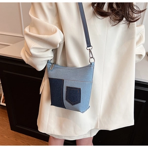 Detailansicht der Denim-Umhängetasche mit dekorativen Taschen und schmalem Riemen