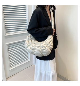 Elegant beige pleated cloud bag worn with a black suit for a stylish urban look