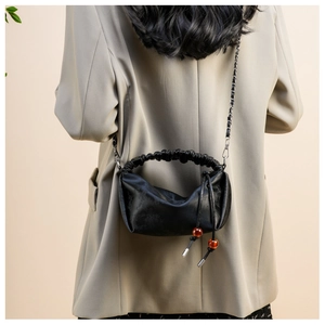 Détail du sac bandoulière plissé noir avec chaîne en métal et perles décoratives