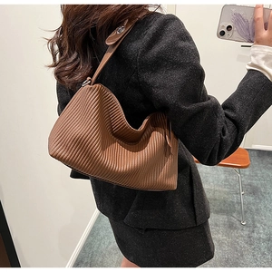 Brown pleated hobo bag detail showing the vertical quilted texture and leather shoulder strap