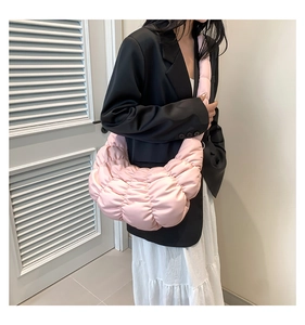 Detail of pink pleated crescent bag showing soft nylon texture on a model shoulder