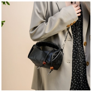 Détail du sac plissé noir avec texture jacquard et cordon à perles d'ambre décoratives