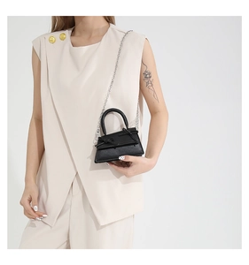 Detail of a black mini square bag with ribbon bow and elegant silver chain strap