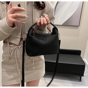 Détail du sac plissé noir en similicuir avec fermeture dorée et bandoulière amovible