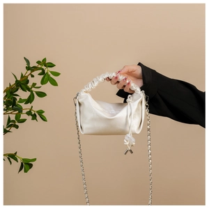 Détail du sac à main beige plissé avec fini satiné doux et bandoulière en chaîne argentée