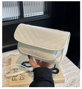 Detail of off-white quilted crossbody bag featuring a black metal chain strap and PU leather
