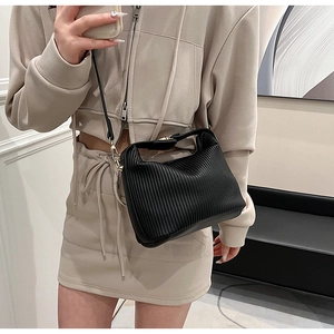 Détail d'un sac bandoulière noir plissé avec garnitures dorées sur une tenue
