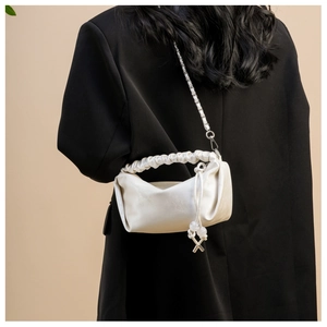 Détail du sac à main plissé crème avec bandoulière métallique et pendentif perlé