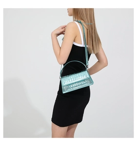Detail of metallic blue textured shoulder bag with stylish embossed pattern on a model