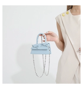 Close-up of light blue mini bag with bow details and silver metal chain strap