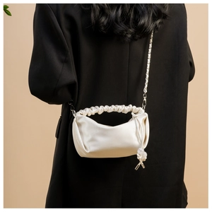 Détail du sac en satin plissé blanc crème avec chaîne en métal et cordon de serrage