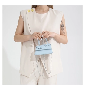 Detailed view of light blue mini handbag with double bow decoration and silver chain strap