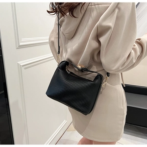 Détail du sac à bandoulière noir aux textures plissées élégantes et finitions dorées