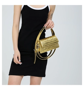 Detail of golden metallic handbag featuring geometric embossed texture and silver hardware