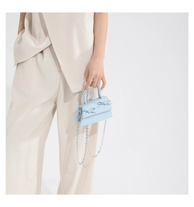 Close-up of light blue mini handbag featuring dual bow details and silver metal chain strap