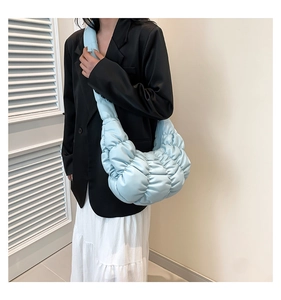 Detail of light blue pleated cloud bag showing quilted texture and wide shoulder strap