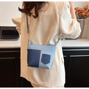 Detail einer Patchwork-Jeans-Umhängetasche mit braunen Nähten an einem Modell