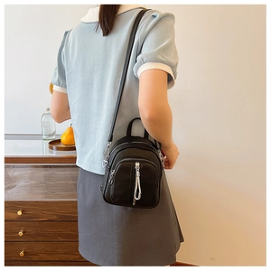 Detail eines kleinen schwarzen Rucksacks mit silbernen Reißverschlüssen und Herzanhänger