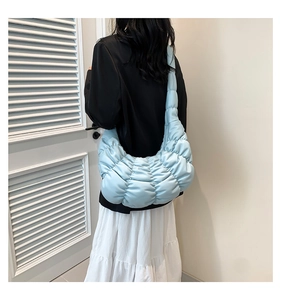 Detail of light blue quilted cloud bag showing draped texture on model's shoulder