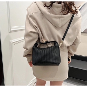 Détail du sac bandoulière plissé noir avec texture en cuir et finitions dorées