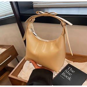 Detail of beige hobo bag showing bow handle design and textured synthetic leather