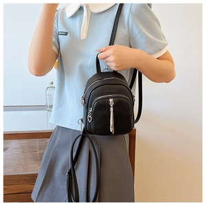 Detail eines schwarzen Mini-Rucksacks mit herzförmigen Reißverschlüssen an einem Modell