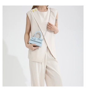 Detail of light blue mini bag with double bows and silver chain strap on model
