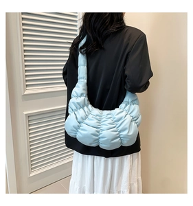 Light blue pleated crescent cloud bag shown worn over the shoulder on a model