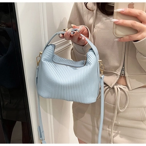 Détail d'un sac à main bleu clair avec texture plissée élégante et boucles métalliques dorées