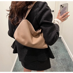 Detailed close-up of beige pleated underarm bag with vertical texture and shoulder strap