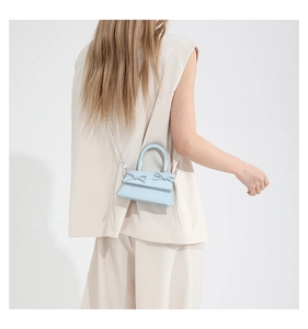 Mini light blue crossbody bag with bow accents worn by model to show size and style