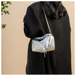 Détail d'un sac bandoulière en satin plissé argenté avec motifs floraux et perles