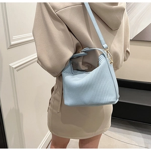 Vue détaillée du sac seau plissé bleu clair montrant la texture et les boucles dorées