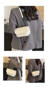 Detail of off-white crossbody bag featuring V-shaped quilting and black chain strap