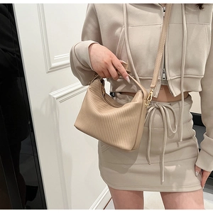 Détail du sac plissé beige montrant la texture verticale et les ferrures dorées