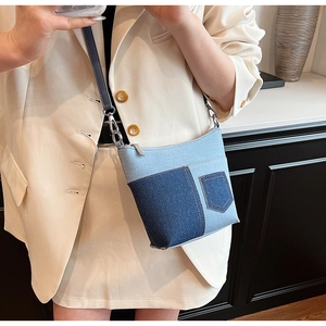 Detail der blauen Denim-Beuteltasche mit Patchwork-Nähten und silbernen Metallteilen