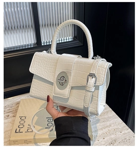 Close-up of white crocodile embossed leather bag with silver buckle and top handle