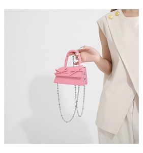 Detailed macro view of pink micro handbag featuring dual bows and silver chain strap