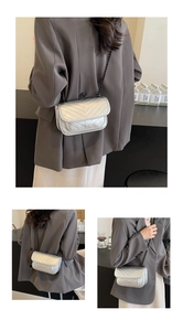 Detailed view of silver quilted crossbody bag with stylish metallic chain strap