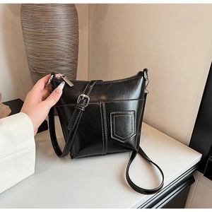 Detailansicht der schwarzen Schultertasche mit Ziernähten und silberner Metallschnalle am Gurt