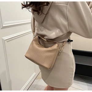 Détail du sac à main plissé beige montrant la texture verticale et les pièces dorées