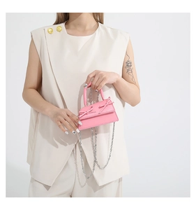 Detailed shot of a pink mini crossbody bag with leather bows and silver chain strap