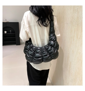 Model view of black pleated puffer shoulder bag showing texture and stylish slouchy fit
