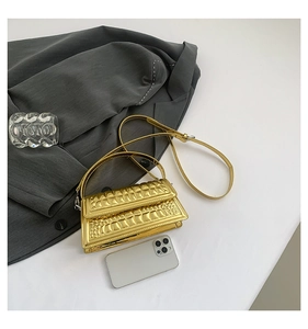 Detail of golden crocodile embossed handbag with glossy metallic finish and shoulder strap