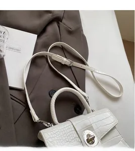 Detail of white crocodile pattern handbag with rotary metal lock and adjustable strap