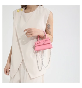 Detail of pink mini handbag featuring double bow accents and silver chain strap