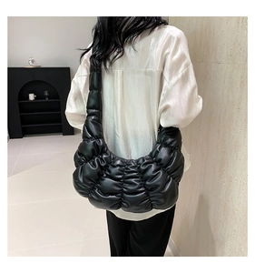 Rear view of model wearing a black pleated dumpling shoulder bag in premium PU leather